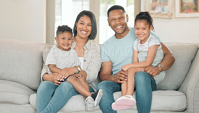 Buy stock photo Shot of a young couple sitting on their sofa at home with their children