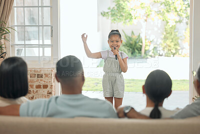 Buy stock photo Shot of an adorable little girl standing in the living room at home and singing for her family