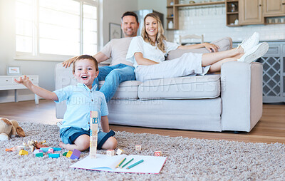 Buy stock photo Shot of a boy playing with his toys while his parents sit on the couch at home