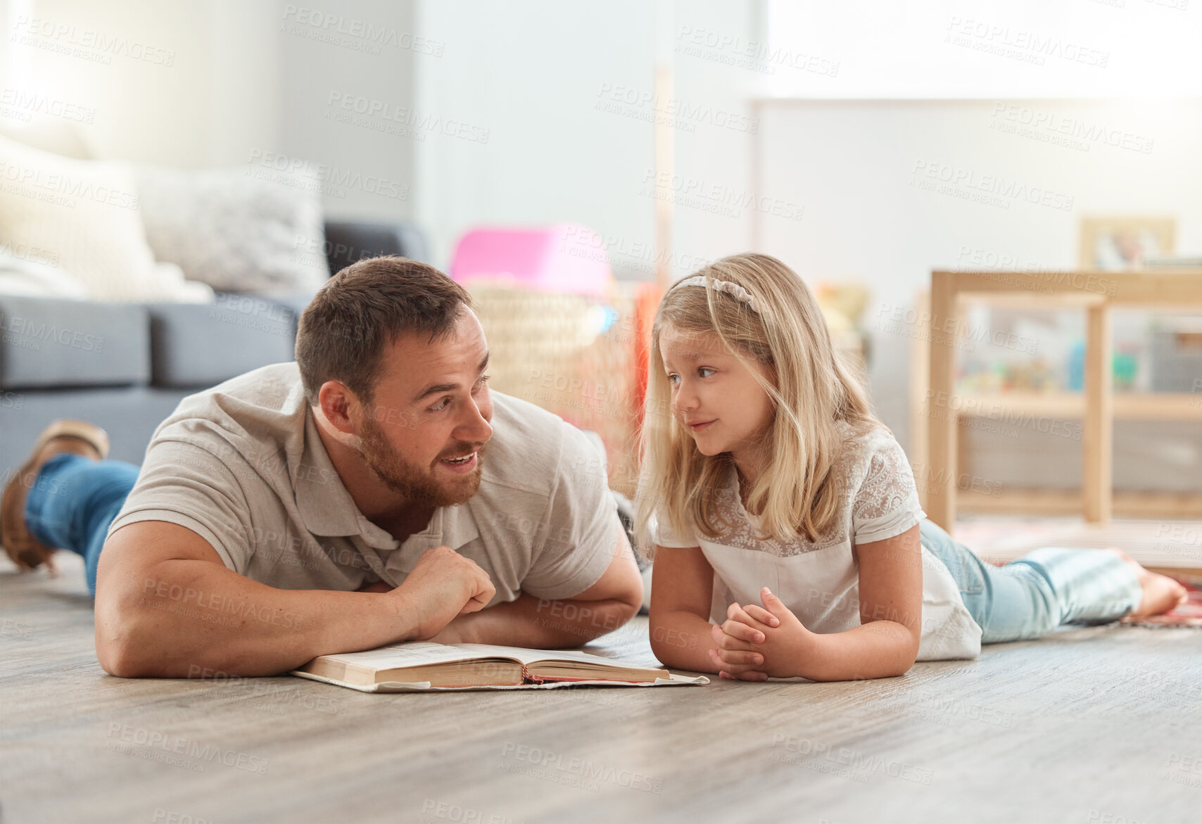 Buy stock photo Shot of a young father and daughter reading a book together at home