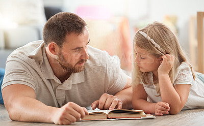 Buy stock photo Shot of a young father and daughter reading a book together at home