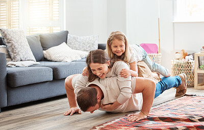 Buy stock photo Shot of a young father doing pushups with his wife and daughter on his back at home