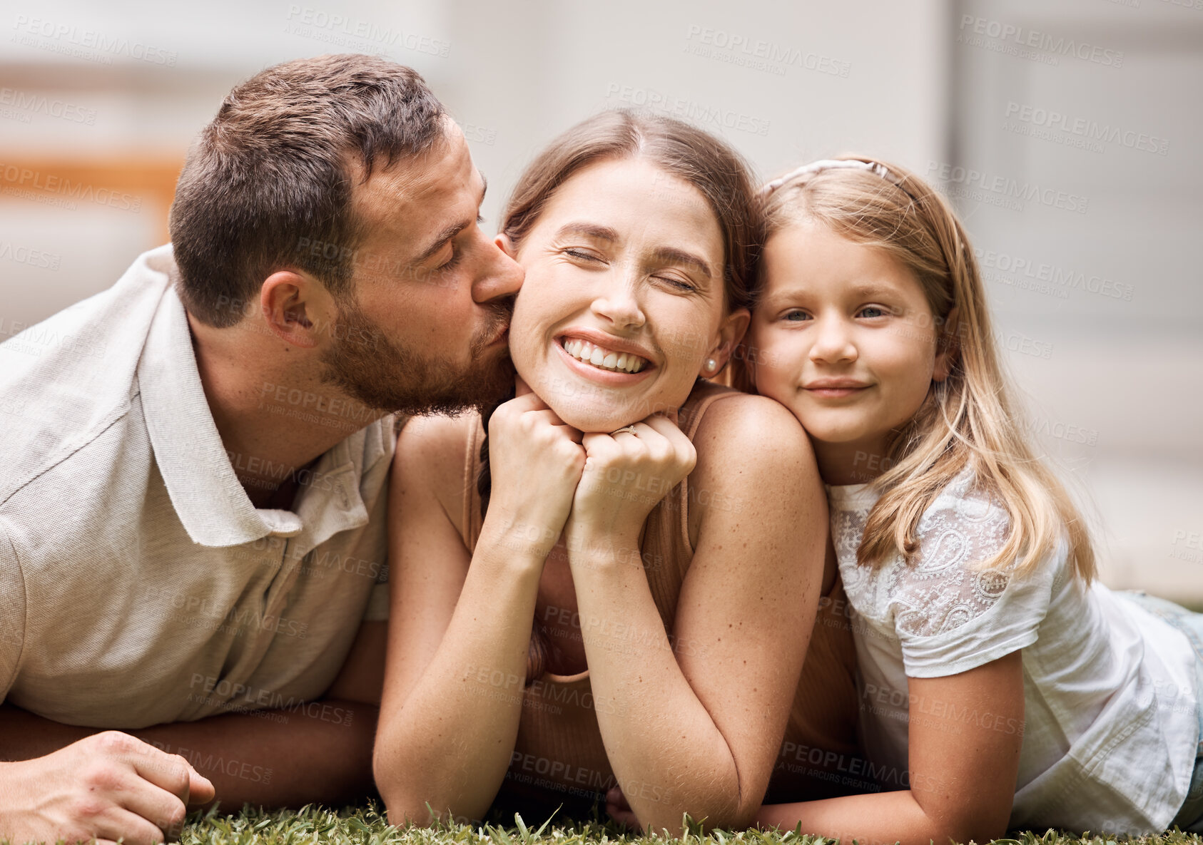 Buy stock photo Shot of a young family lying on the grass in their garden and bonding during a day at home