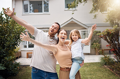 Buy stock photo Shot of a young couple standing outside and posing with their daughter in front of their house