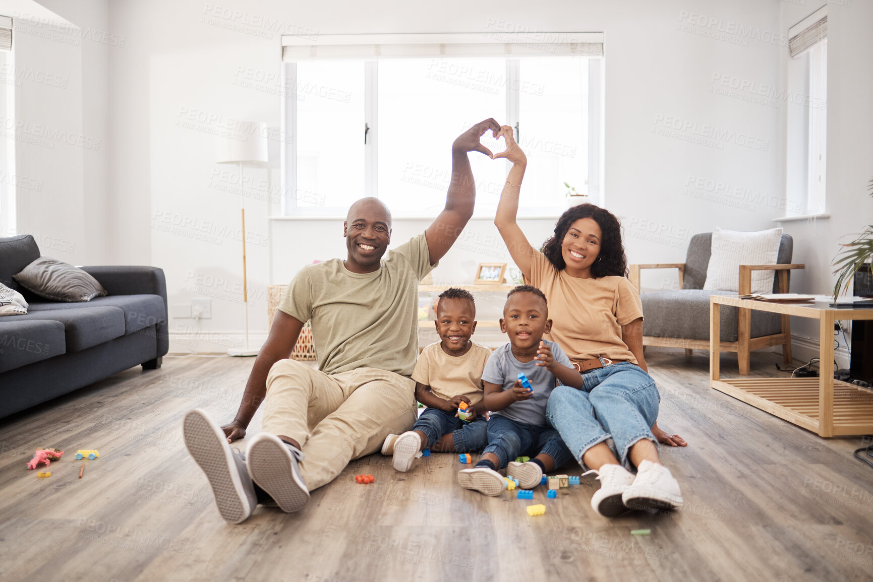 Buy stock photo Shot of a happy young family making a heart shaped gesture above themselves during play time at home