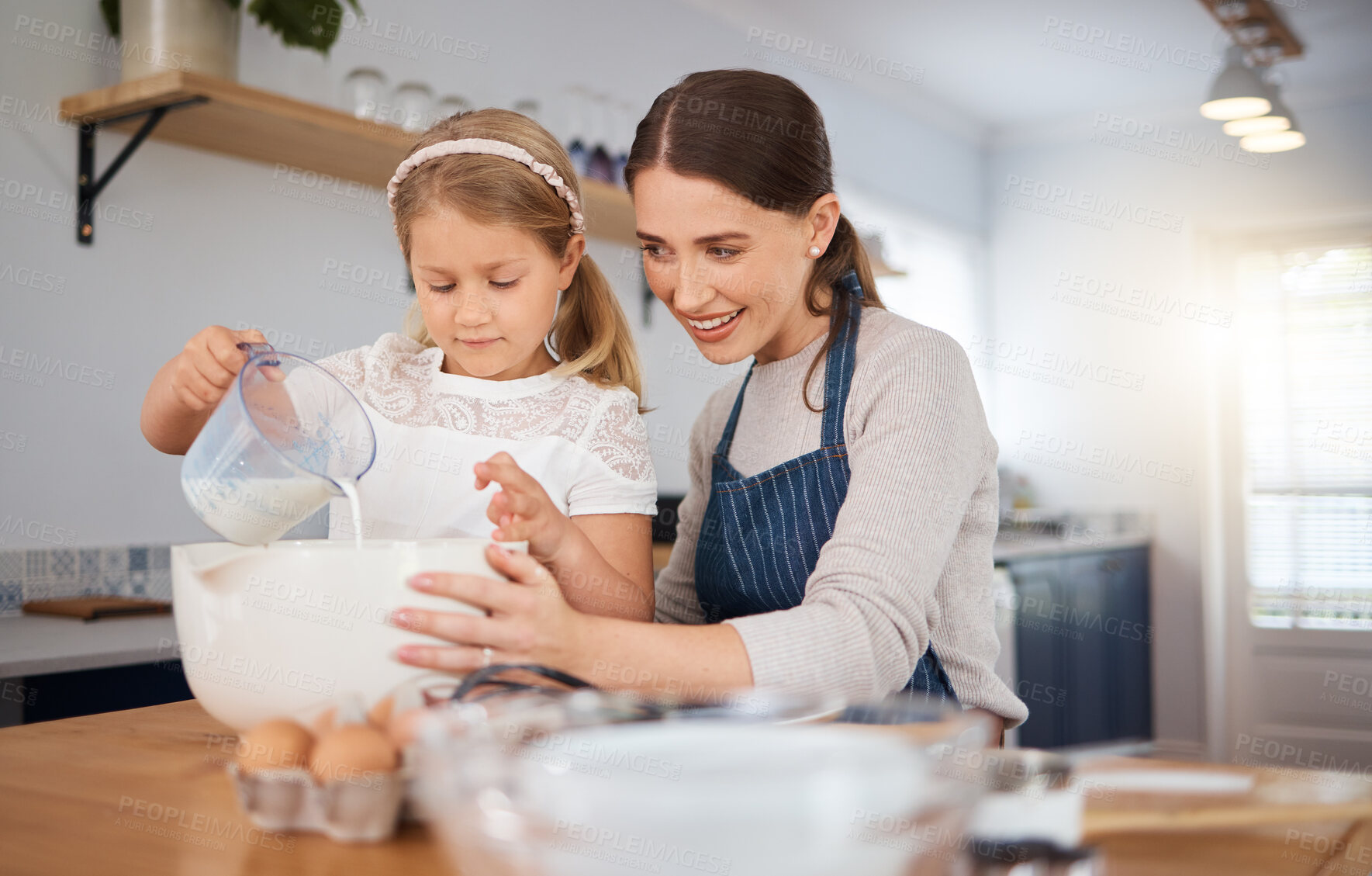Buy stock photo Shot of an adorable little girl assisting her mother while baking at home