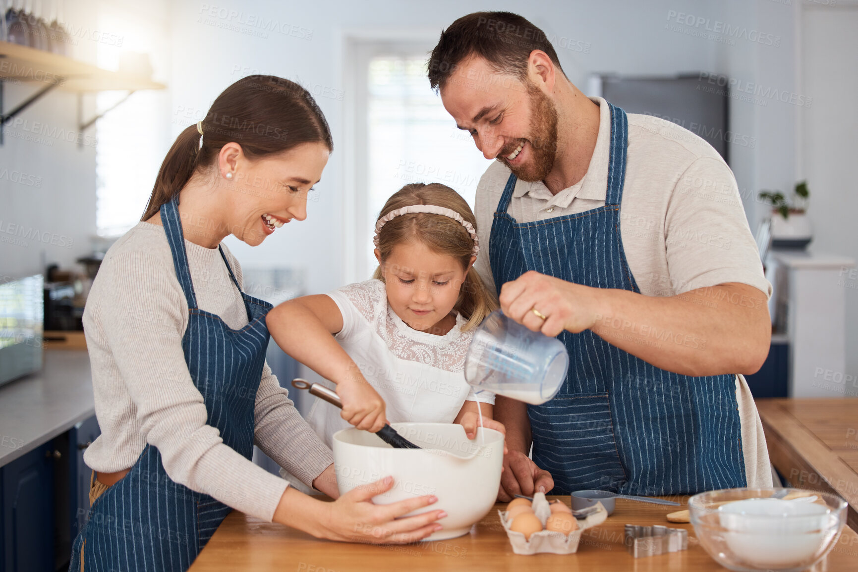 Buy stock photo Shot of a young couple and their daughter baking together at home