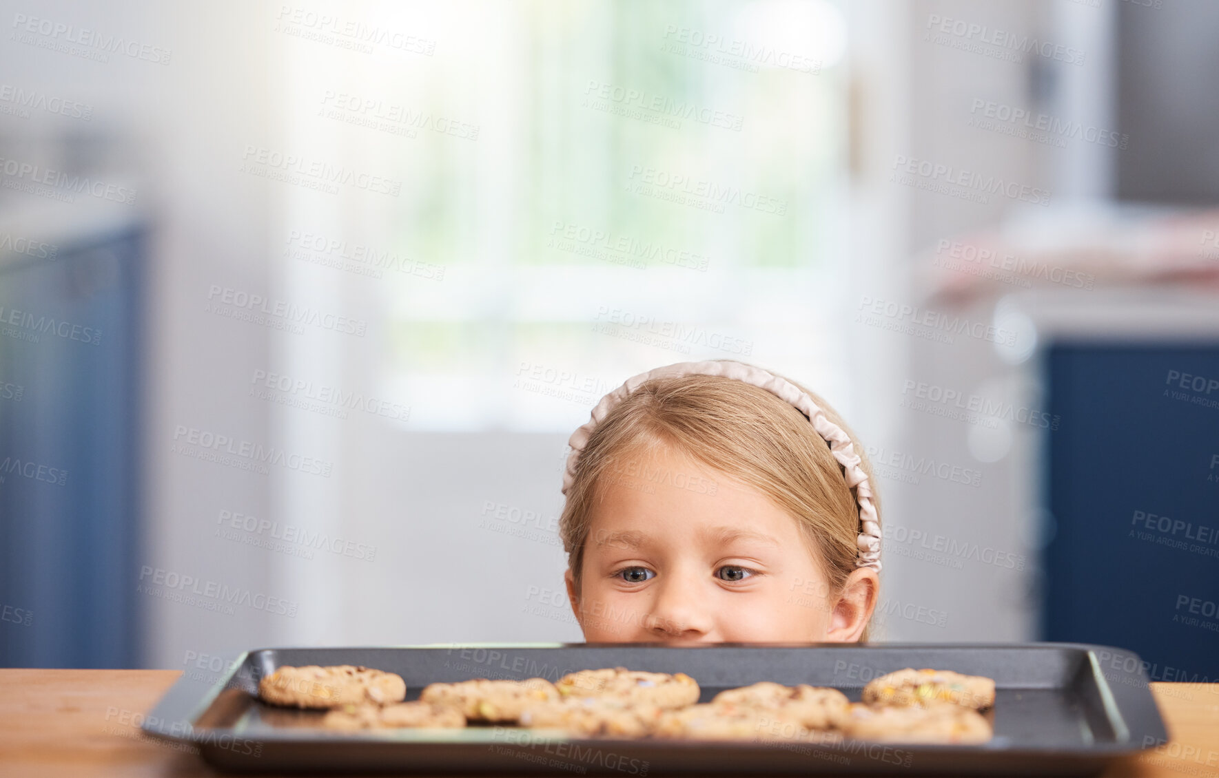 Buy stock photo Girl child, kitchen or table with cookies or hungry eyes for snack, youth with idea in house. Kid, home or naughty thought for baking tray on wood with biscuits, excited check on desert for eating