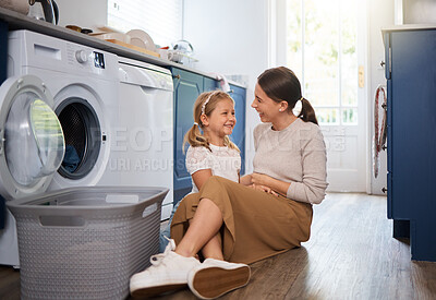 Buy stock photo Shot of a woman sitting with her daughter while doing laundry at home