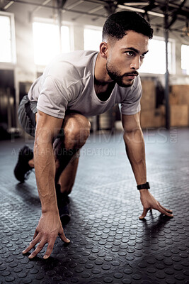 Buy stock photo Shot of a sporty young man stretching his legs while exercising in a gym