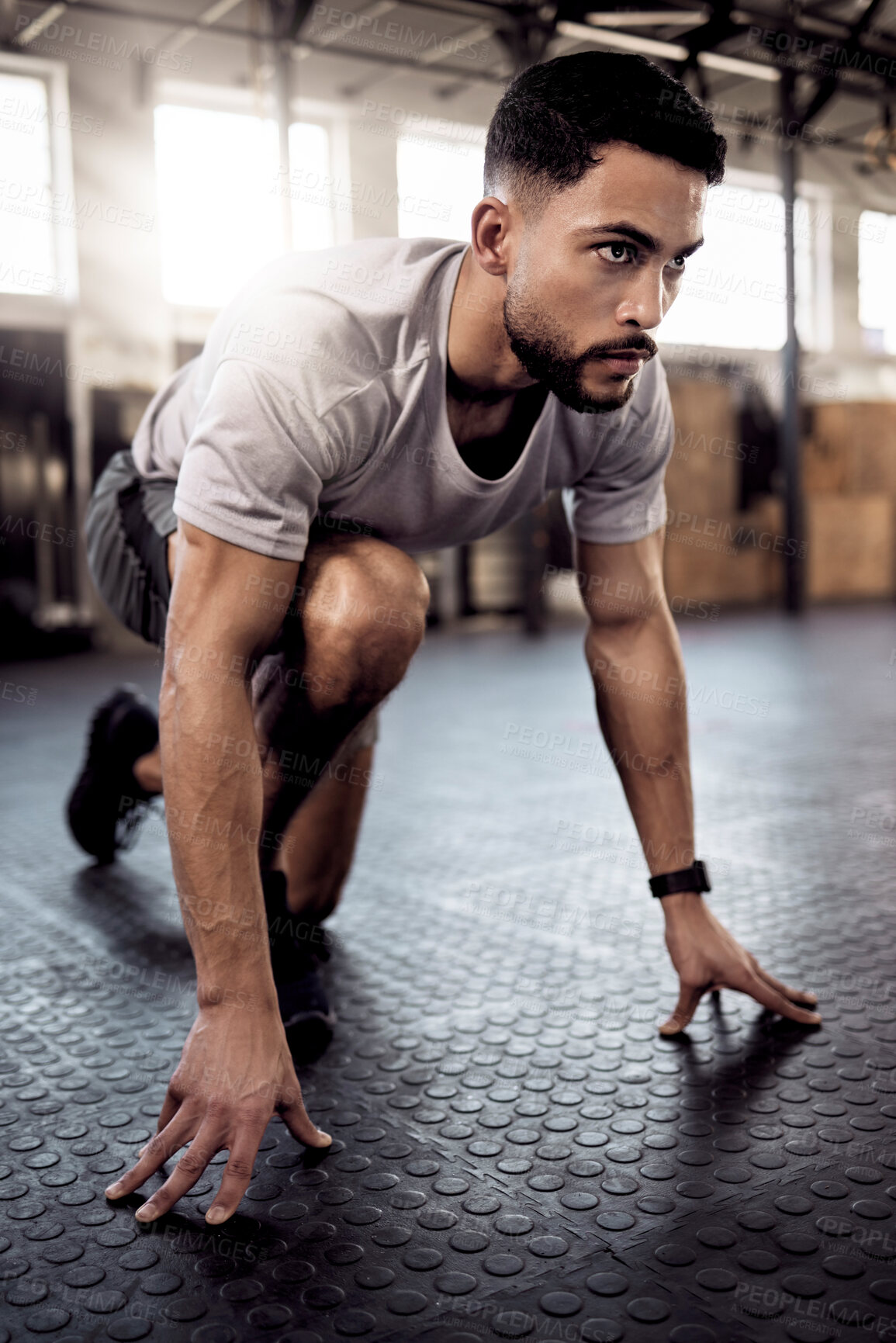 Buy stock photo Shot of a sporty young man stretching his legs while exercising in a gym