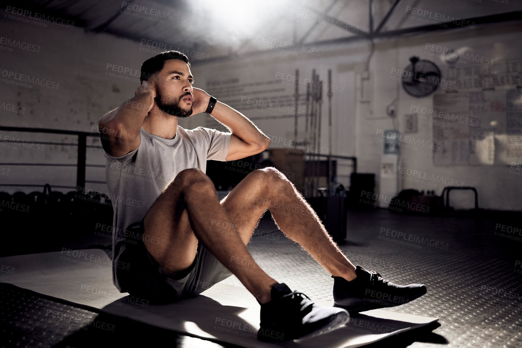 Buy stock photo Shot of a young man doing crunches in a gym