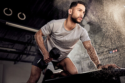 Buy stock photo Shot of a muscular young man exercising with a dumbbell in a gym