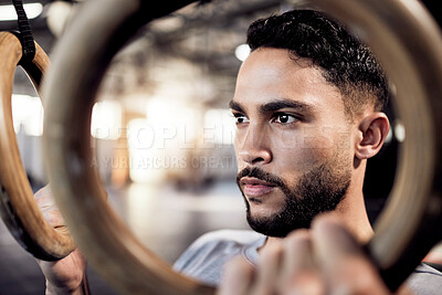 Buy stock photo Athlete man, gymnastic rings and gym for a training workout with focus and commitment. Face of serious male person with pull up exercise for strong muscle, power and fitness training with balance