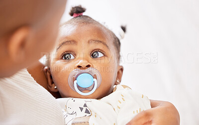 Buy stock photo Shot of an adorable baby girl sucking a dummy while being held by her mother at home