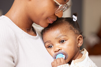 Buy stock photo Shot of an adorable baby girl sucking a dummy while being held by her mother at home