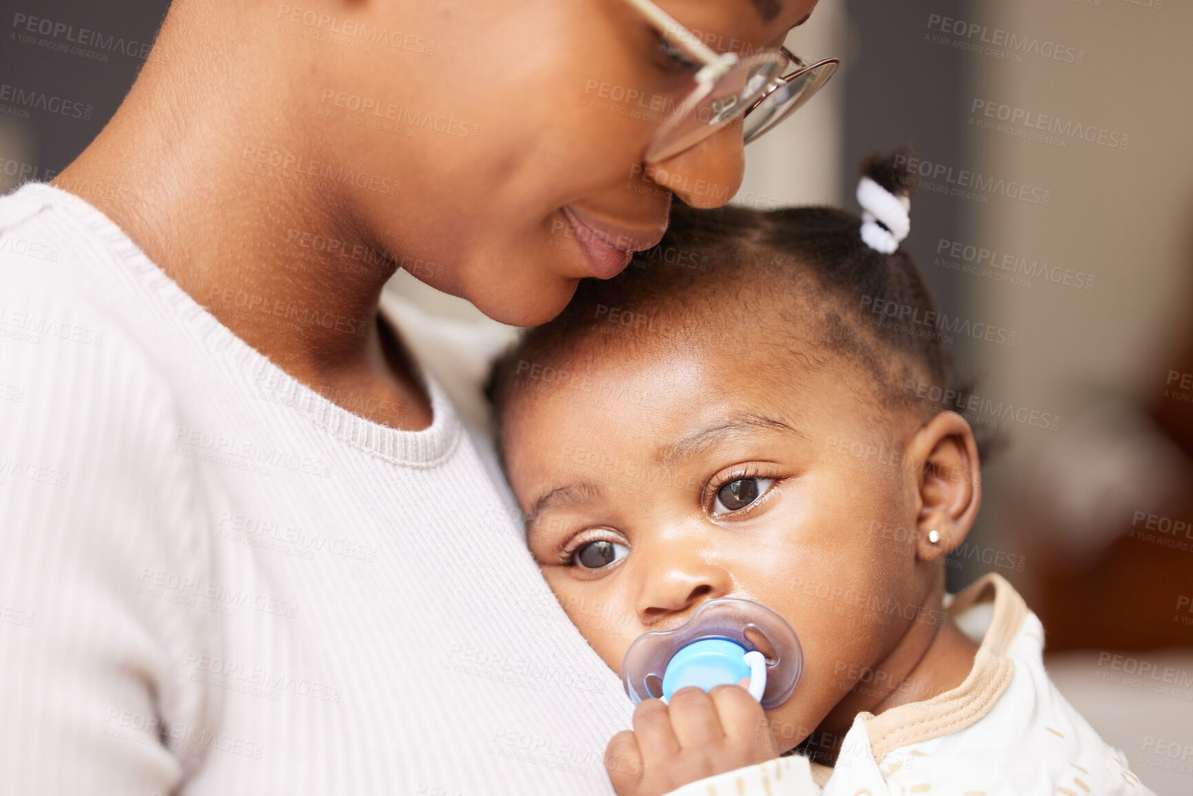 Buy stock photo Shot of an adorable baby girl sucking a dummy while being held by her mother at home