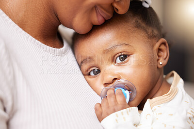 Buy stock photo Portrait of an adorable baby girl sucking a dummy while being held by her mother at home