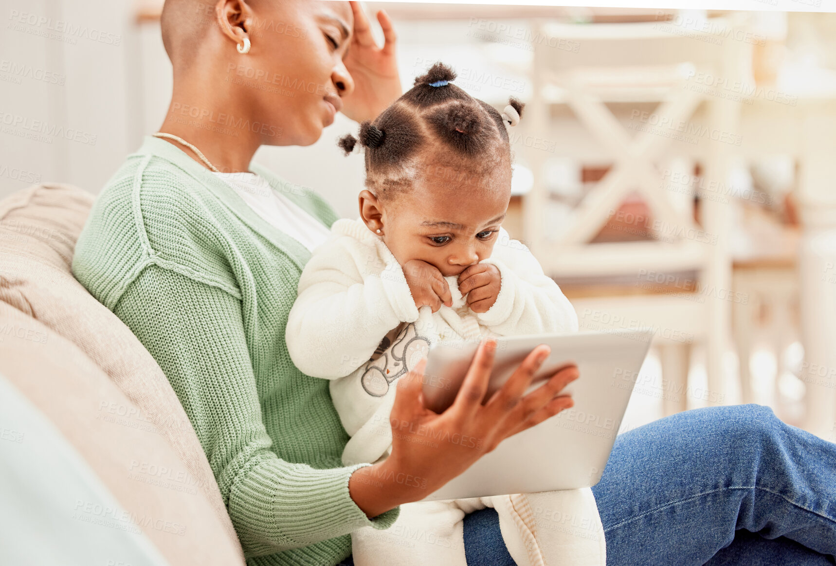 Buy stock photo Cropped shot of a young woman entertaining her daughter with a tablet while suffering with a headache on the sofa at home