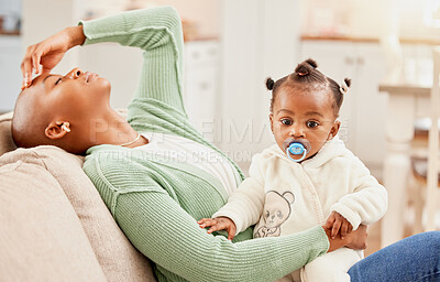 Buy stock photo Cropped shot of a young woman sitting on the sofa her daughter while suffering with a headache