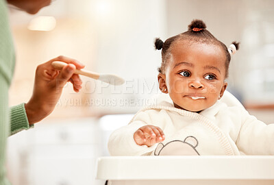 Buy stock photo Cropped shot of an adorable little girl being fed by her mother in the kitchen at home