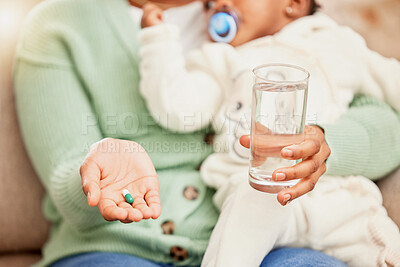 Buy stock photo Cropped shot of an unrecognizable woman taking medication while sitting on the sofa with her daughter