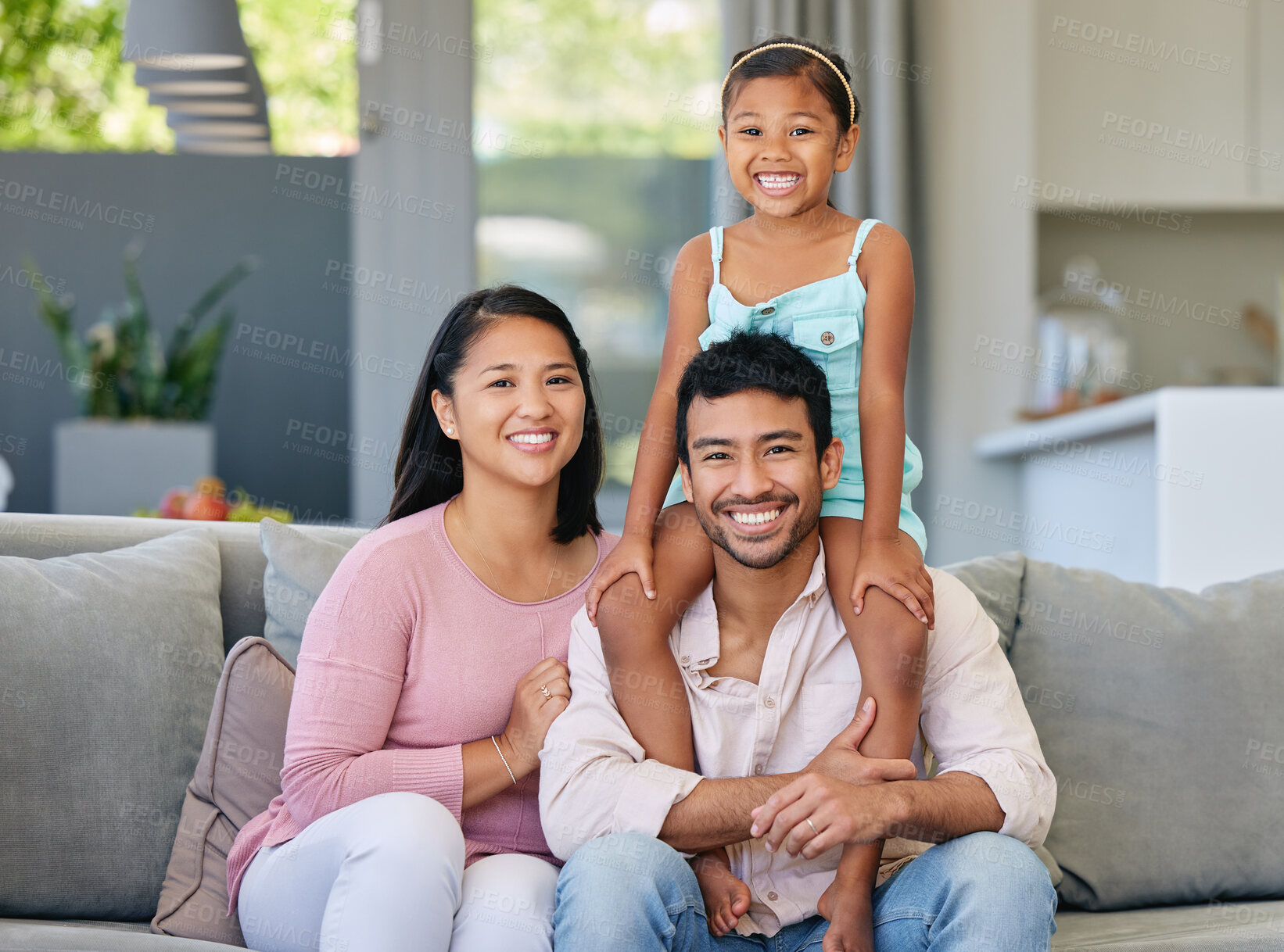 Buy stock photo Portrait, parents and asian child on sofa with smile, bonding and relax together in living room on weekend. Mom, dad and girl on shoulders with love, trust and support in modern home in Indonesia.