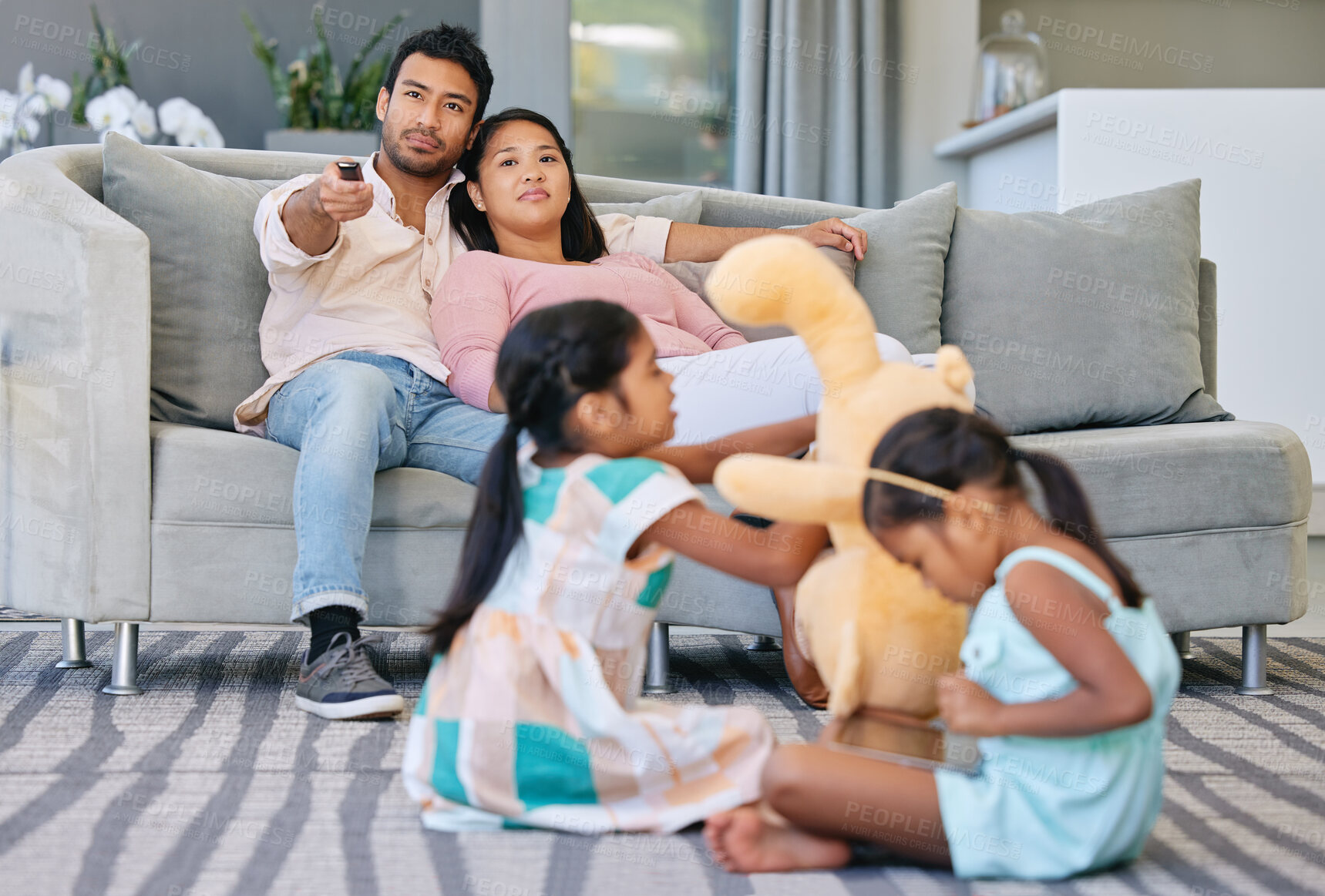 Buy stock photo Relax, parents and kids on couch with busy family, watching tv and bonding together in smart home. Mom, dad and girl children on sofa playing with tablet, toys and online connectivity in living room.