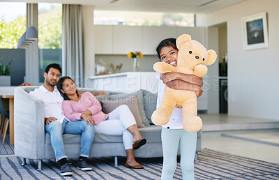 Buy stock photo Shot of a little girl holding her teddy bear while her parents look on