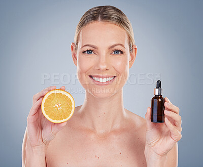 Buy stock photo Studio portrait of an attractive young woman posing with half an orange and facial serum against a grey background