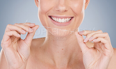Buy stock photo Studio shot of an unrecognizable young woman using dental floss against a grey background