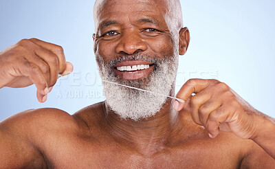 Buy stock photo Studio portrait of a mature man flossing his teeth against a blue background