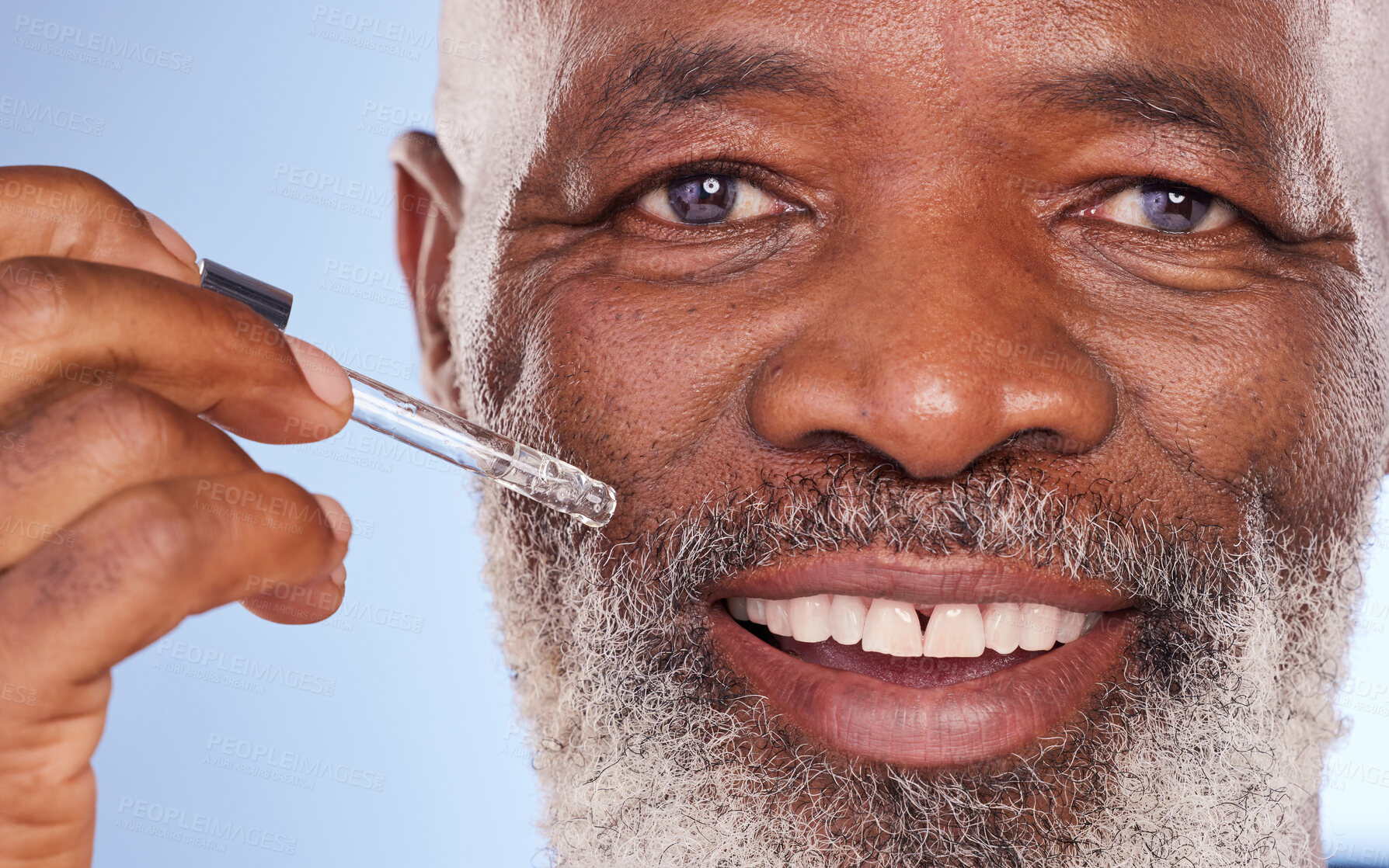 Buy stock photo Studio portrait of a mature man applying serum to his face against a blue background