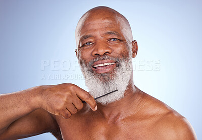 Buy stock photo Studio portrait of a mature man combing his grey beard against a blue background