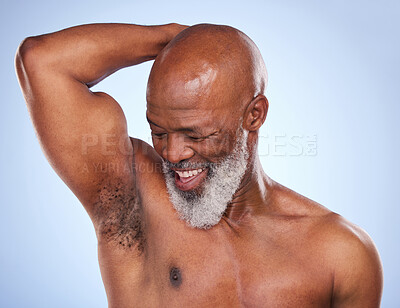 Buy stock photo Studio shot of a mature man drying his armpit after applying deodorant against a blue background
