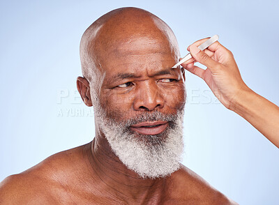 Buy stock photo Studio shot of a mature man having his eyebrow tweezed by an unrecognizable woman  against a blue background