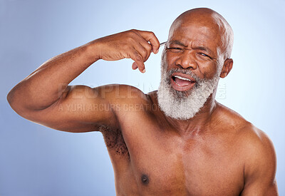Buy stock photo Studio portrait of a mature man tweezing his eyebrow against a blue background