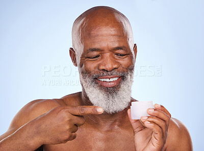 Buy stock photo Studio shot of a mature man holding face moisturiser in his hand against a blue background