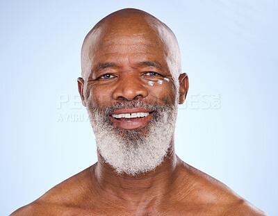 Buy stock photo Studio portrait of a mature man applying moisturiser to his face against a blue background
