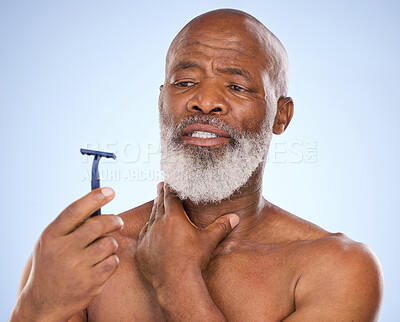 Buy stock photo Pain, shaving and black man with razor for beard in studio for grooming, hair removal or self care treatment. Injury, clean and mature person with shaver for facial shaving routine by blue background