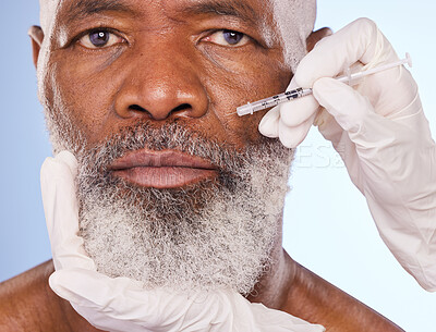 Buy stock photo Studio portrait of a mature man getting his face injected by gloved hands against a blue background