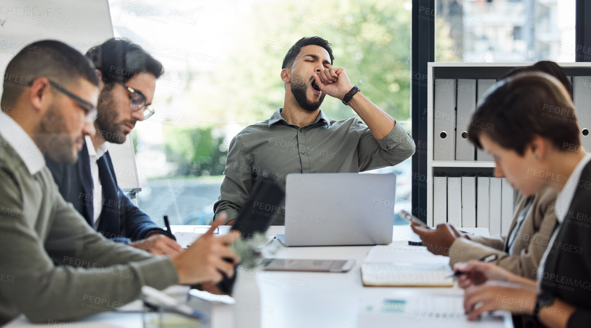 Buy stock photo Shot of a young businessman yawning in a meeting at work