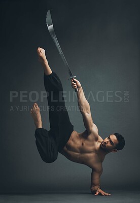 Buy stock photo Full length shot of a handsome young man performing a martial arts kick with a broadsword in the studio