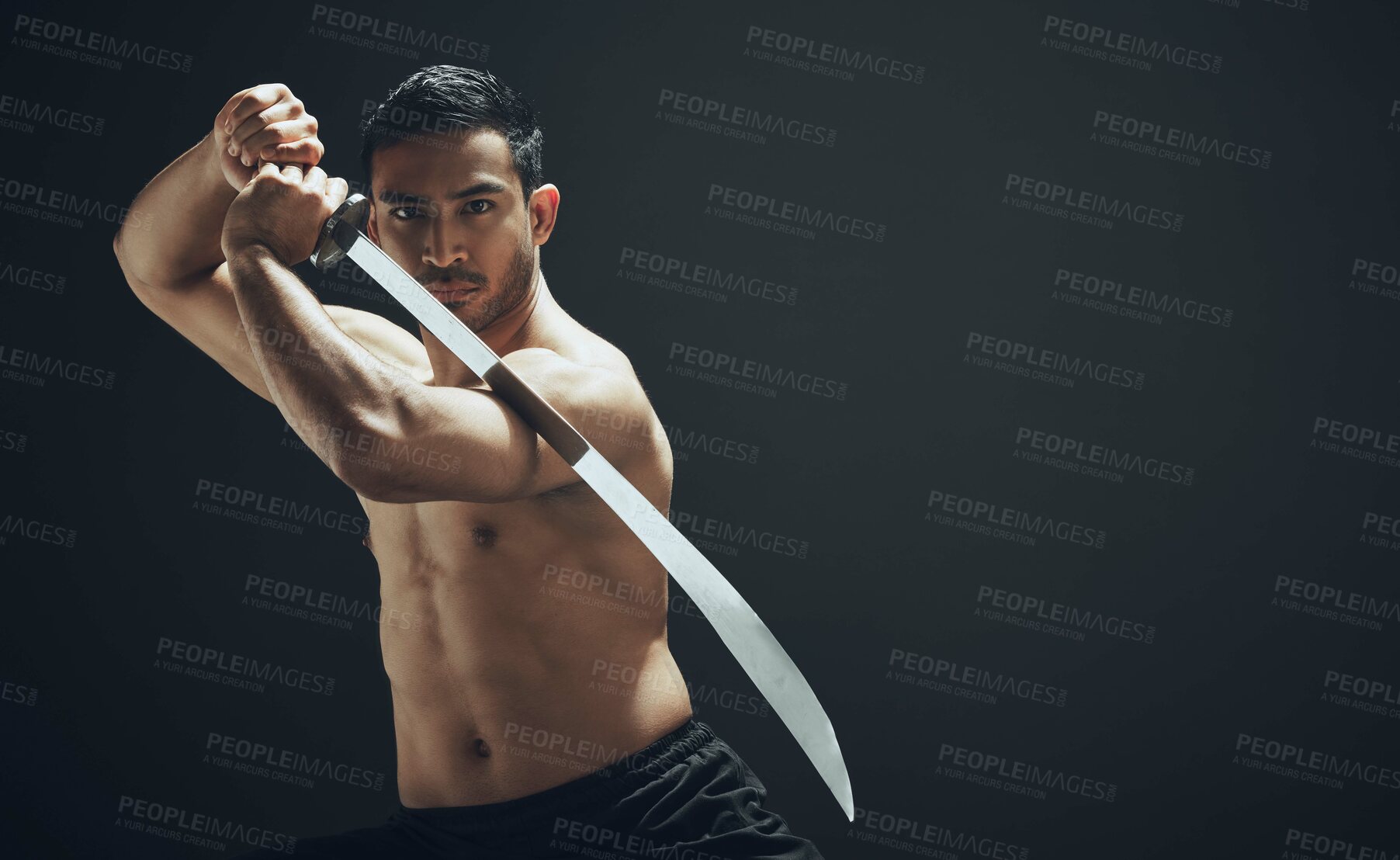Buy stock photo Shot of a handsome young man standing alone in the studio and posing with a broadsword
