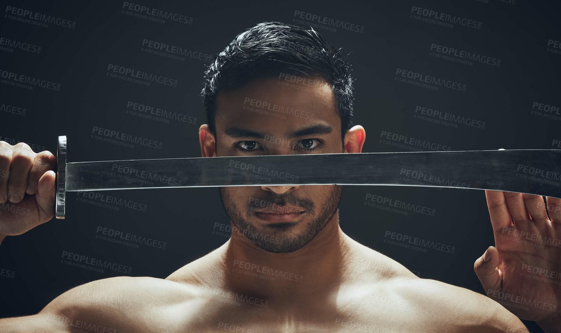 Buy stock photo Shot of a handsome young man standing alone in the studio and posing with a broadsword