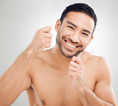 Buy stock photo Portrait, smile and man flossing for hygiene with healthcare and plaque removal in studio. Cleaning teeth, Asian guy and dental string for healthy gums and gingivitis prevention by white background