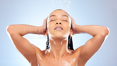 Buy stock photo Studio shot of an attractive young woman washing her hair while taking a shower against a blue background