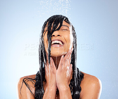 Buy stock photo Studio shot of an attractive young woman taking a shower against a blue background