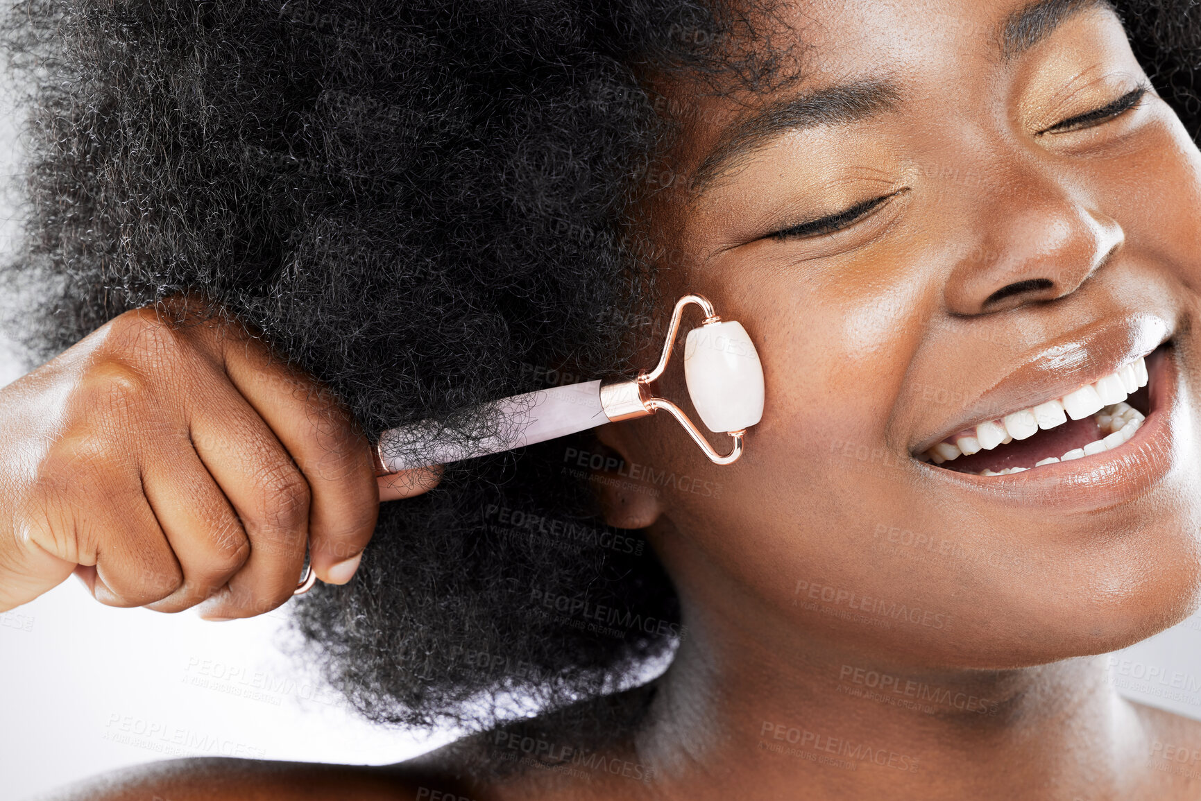 Buy stock photo Studio shot of an attractive young woman using a jade roller on her face against a grey background