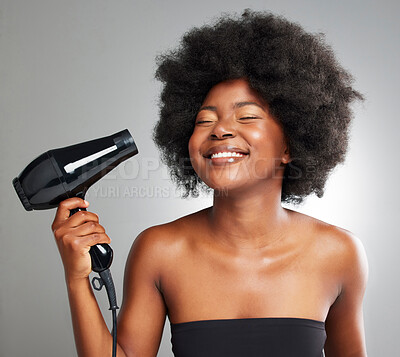 Buy stock photo Smile, black woman and hair care with hairdryer in studio for afro beauty, growth and natural texture of salon treatment. African, female person and electric appliance, shine and grey background